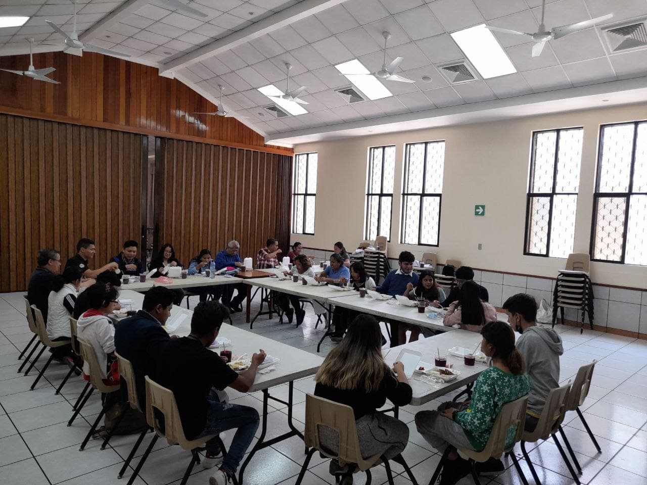 Salón de una iglesia con mesas llenas de personas almorzando comida de La Silenciosa