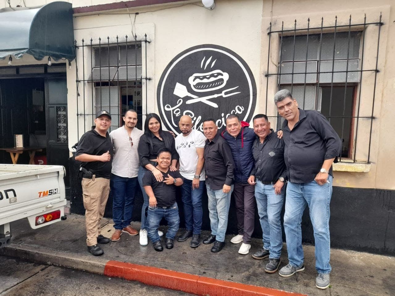 El equipo de La Silenciosa posando frente al mural del logo del restaurante